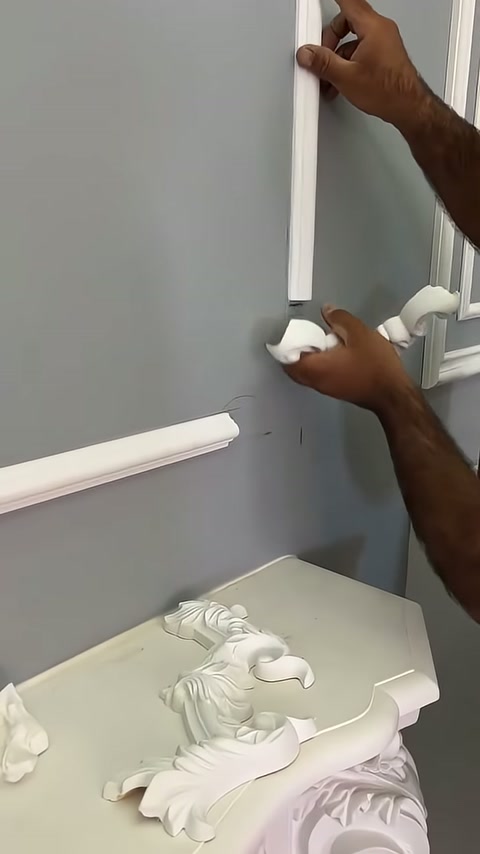 A decorative corner piece is being manually placed at the end of a horizontal profile