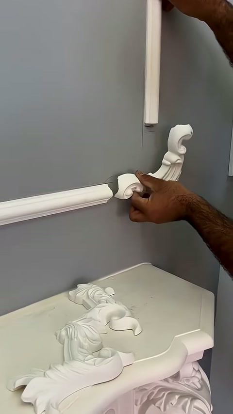 A craftsman brings a curved ornament alongside the horizontal wall profile