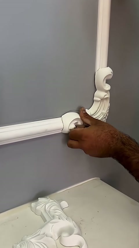 The lower section of the corner ornament is being pressed onto the horizontal profile