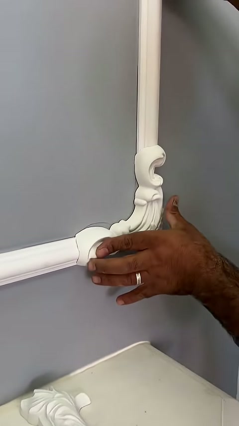 A curved white motif is being manually supported at the end of the horizontal trim