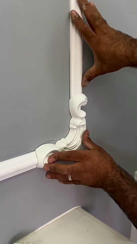 A decorative junction element is being carefully adjusted between two profiles