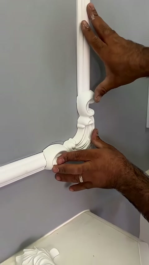 A craftsman presses the corner motif against the vertical and horizontal trim