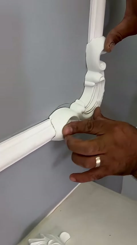 A craftsman aligns the lower edge of the leaf-patterned piece with the trim
