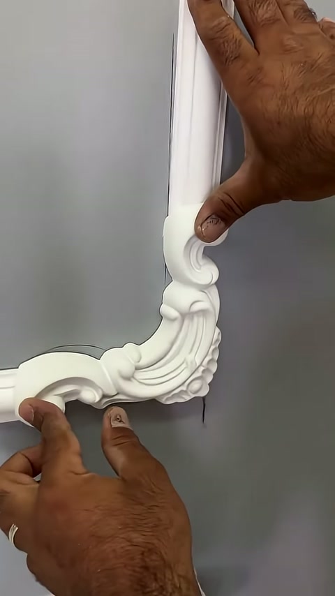 The curved edge of the corner ornament is being adjusted relative to the white trim