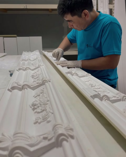 Operaio che rifinisce a mano una cornice ornamentale intagliata a rilievo