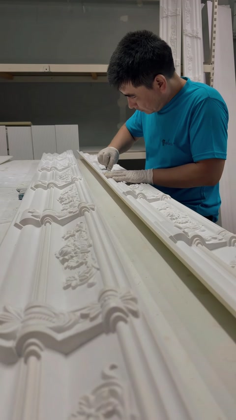 Operaio che rifinisce a mano una cornice ornamentale intagliata a rilievo