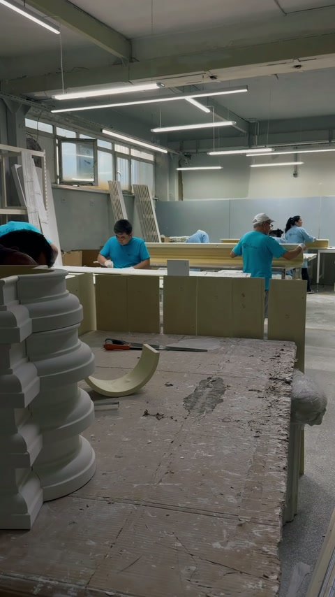 L'officina di finitura mostra artigiani che modellano cornici decorative ai banchi di lavoro