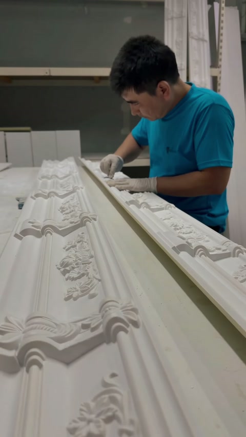 Artigiano che perfeziona il rilievo floreale lungo una lunga cornice ornamentale