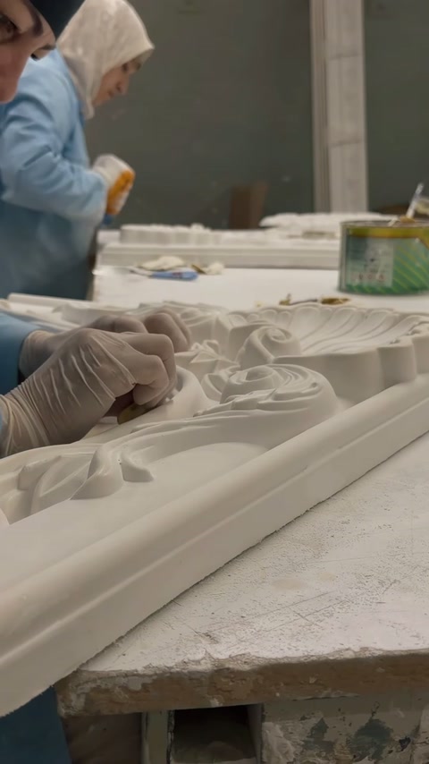 Artigiano che applica tratti di finitura accurati all'ornamentazione floreale in rilievo