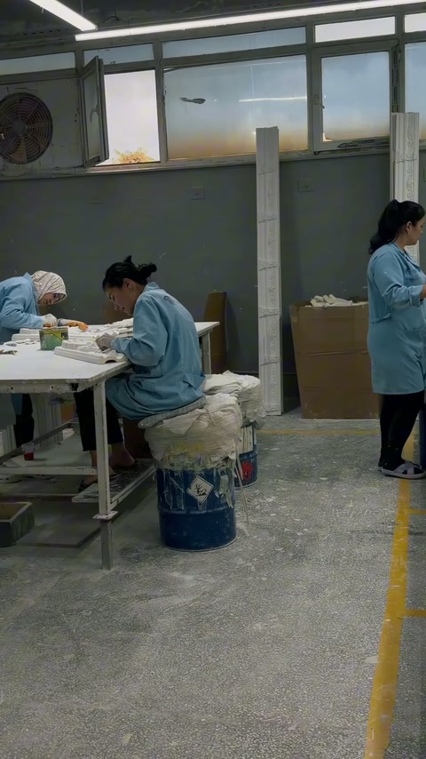 Artigiani che rifiniscono elementi decorativi architettonici attorno a un tavolo da lavoro condiviso