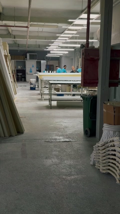 Il corridoio di produzione contiene tavoli di lavoro, profili impilati e componenti curvi rifiniti