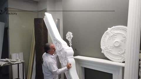 The craftsman displays a long decorative polyurethane piece vertically in the workshop