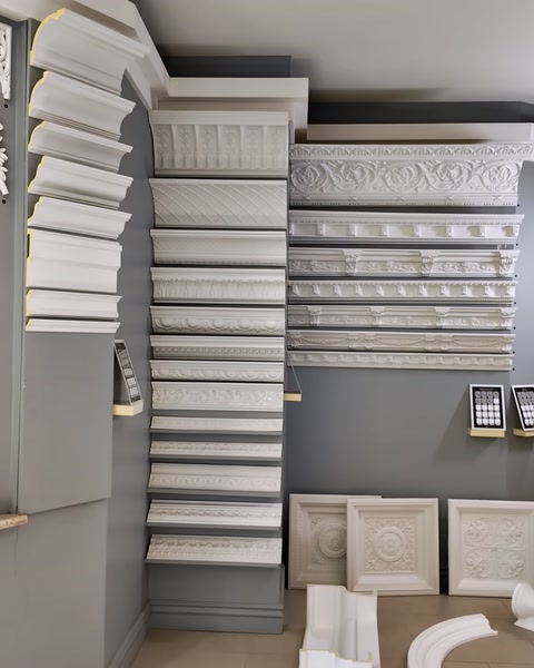 Crown molding and architectural trim models are displayed in tiers on the wall