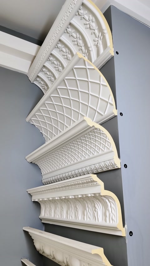 Processed cornice models with cross-sections are arranged on the showroom wall.