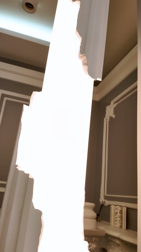 Indented edges of the illuminated decorative piece are examined in front of ceiling and wall.