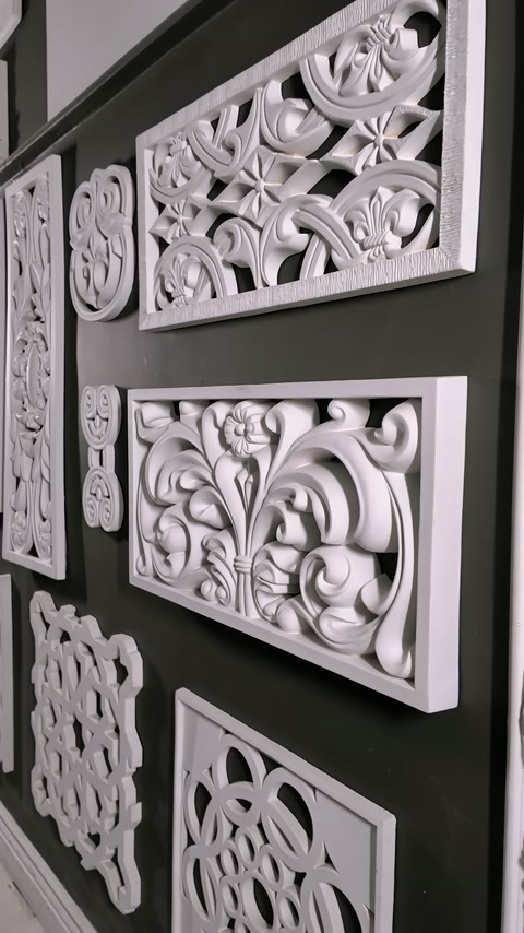 Carved panels of various sizes are mounted on a dark display wall.
