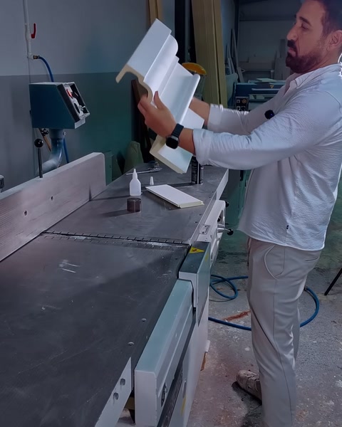 Un pezzo di cornice a L tenuto in mano con la colla pronta sul banco