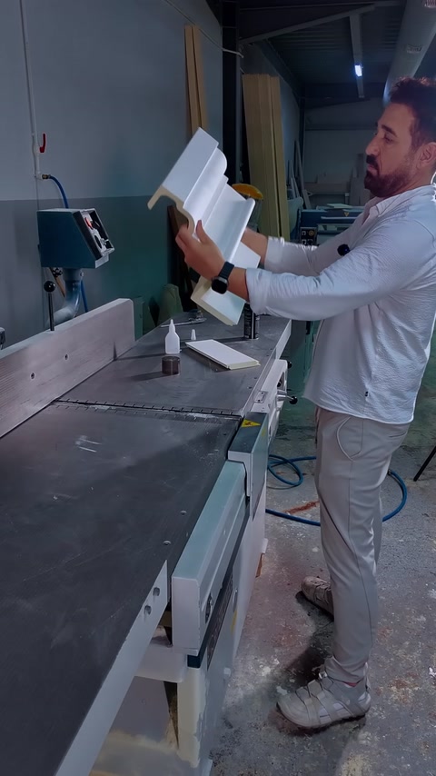 Un pezzo di cornice a L tenuto in mano con la colla pronta sul banco
