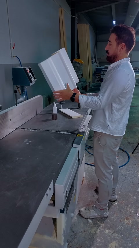 Craftsman holds the assembled cornice corner upright beside the workshop saw.