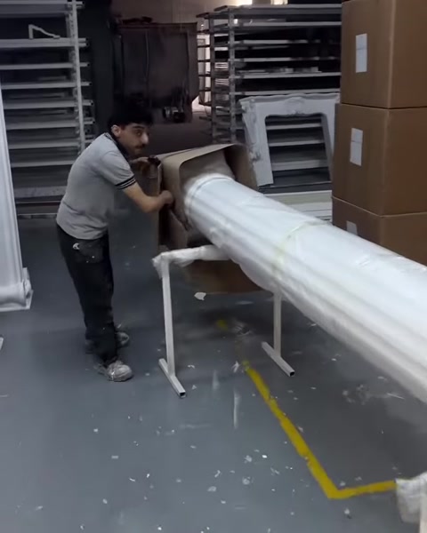 Un operatore separa con attenzione il lungo fusto scanalato della colonna dal cartone