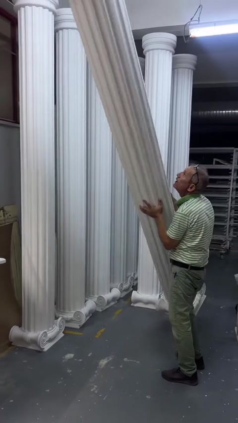 Un operatore inclina una lunga colonna decorativa dalla posizione verticale durante la movimentazione