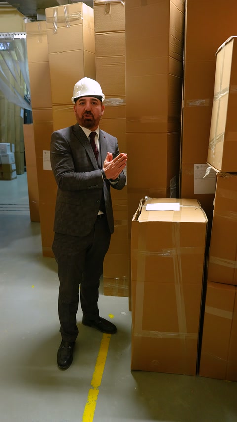 L'addetto spiega l'ispezione pre-consegna tra i mucchi di scatole.