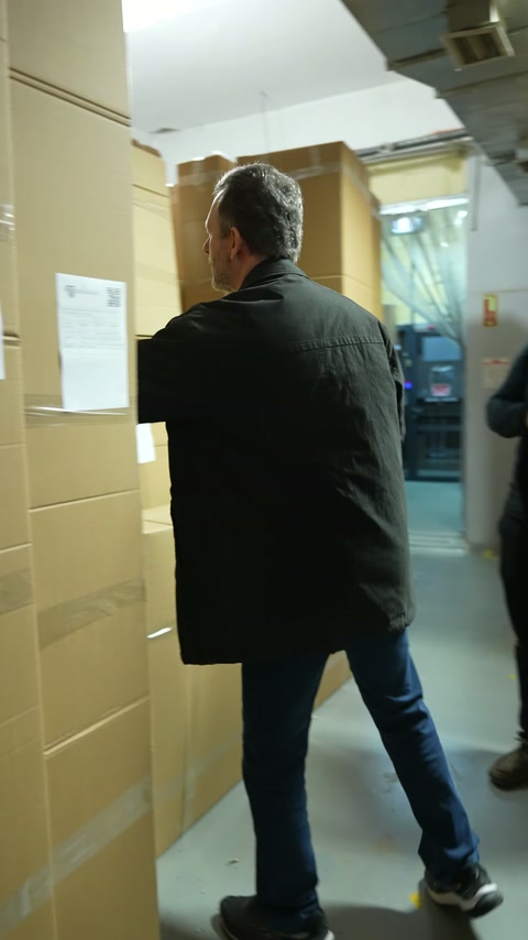 Il cliente si dirige verso i lunghi pacchetti di cartone nel deposito della fabbrica.