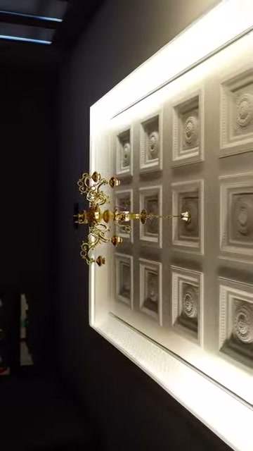 Su un soffitto illuminato si vedono cassettoni quadrati e centri di rosoni in rilievo