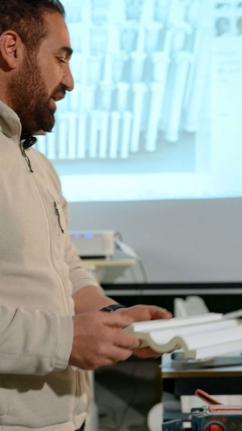 Craftsman examines a small decorative profile piece near the cutting machine