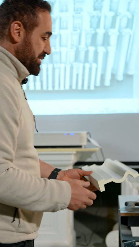 Craftsman holds a profile sample while explaining the cutting detail