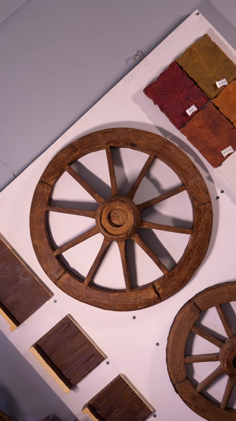 Replica decorativa di ruota di carro accanto a campioni di tonalità di legno