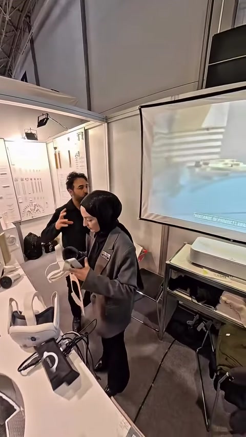 Un addetto illustra il progetto del modellino ai visitatori con il supporto di uno schermo.