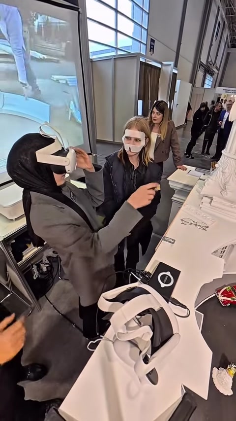 A un visitatore viene indossato un visore VR per esplorare il modellino architettonico.