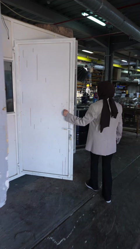 An employee carries a large white window module through the workshop