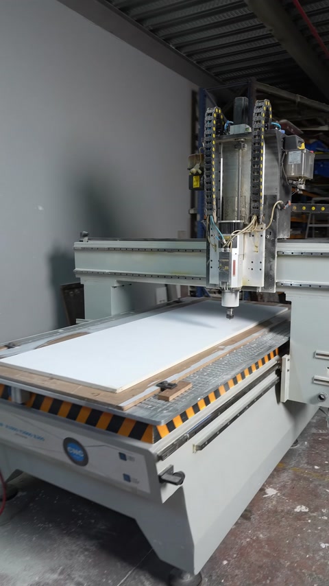 A wide panel is placed on the worktable of the CNC machine
