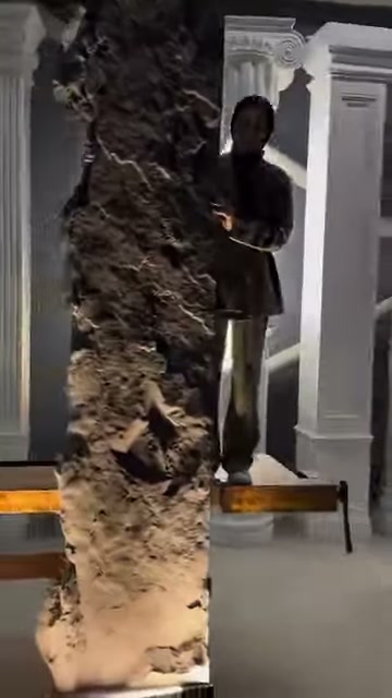 A long rock-look panel is held vertically in a display area with decorative columns