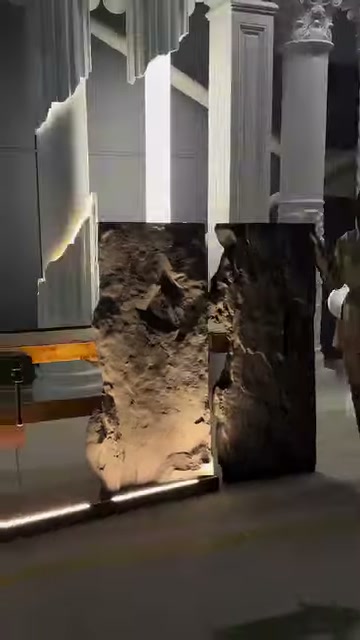 An illuminated rock-look panel and a dark rear surface stand side by side