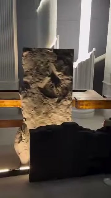 The horizontally held dark panel partially covers the bottom of the illuminated stone texture