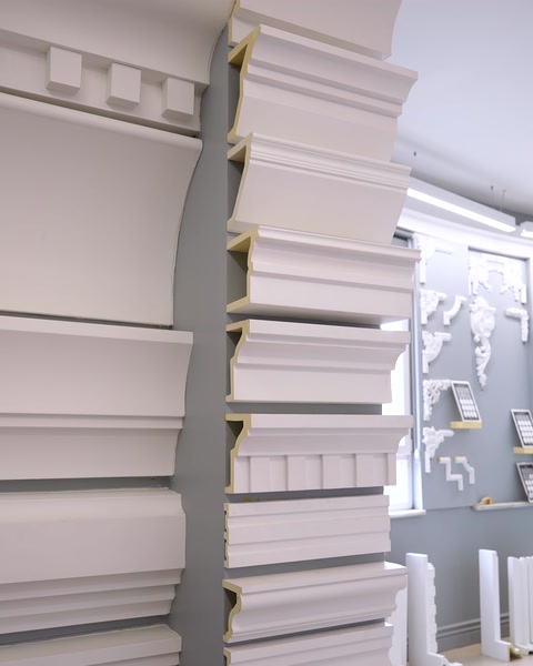 Multiple decorative cornice moldings stacked along gray showroom wall