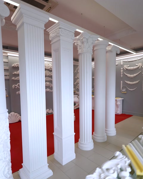 Row of white fluted showroom columns lining red carpet aisle