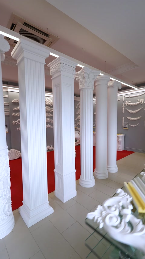 Row of white fluted showroom columns lining red carpet aisle