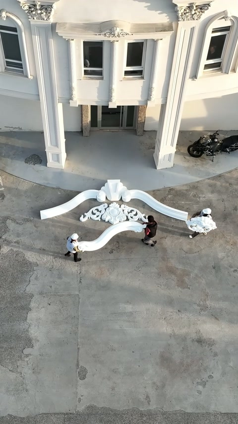 I membri dell'equipaggio allineano decorazioni a voluta all'interno della cornice curva superiore.