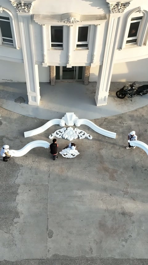 Gli operai perfezionano l'arrangiamento della corona di facciata superiore nel cortile pavimentato.