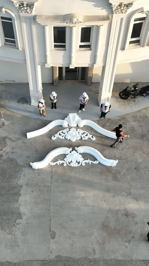 I membri dell'equipaggio si allontanano dalle due corone decorative di facciata allineate.