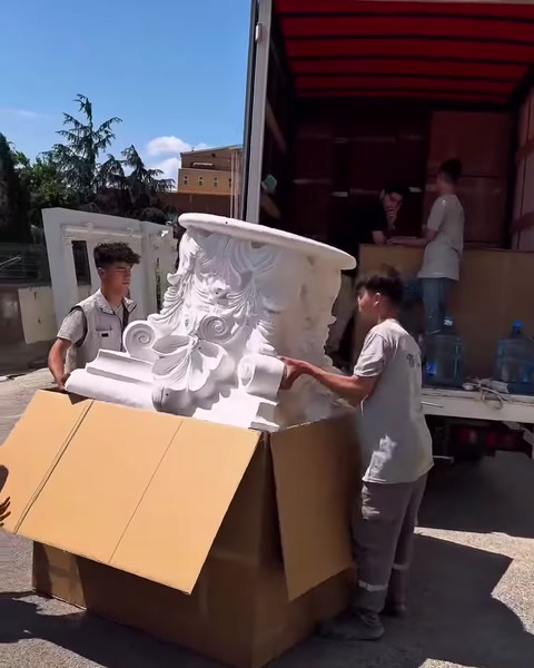 Due operatori estraggono insieme il grande capitello decorativo dalla scatola