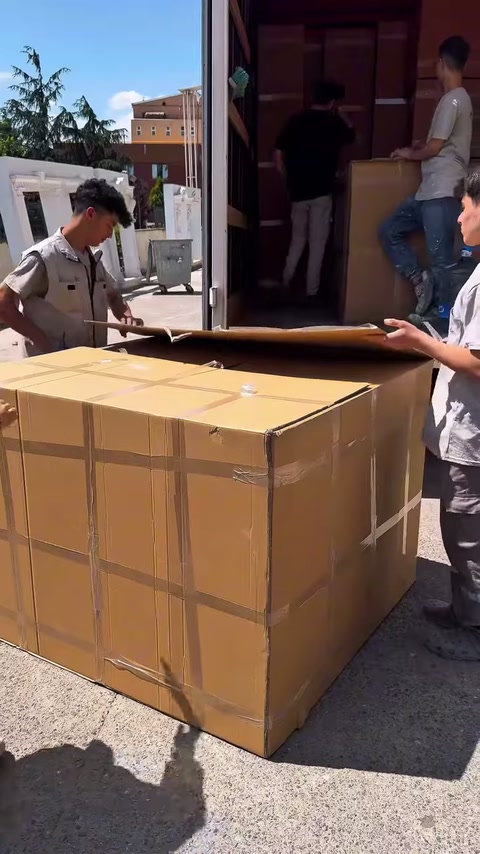 Un addetto tira la reggetta della scatola mentre gli altri tengono fermo l'imballaggio
