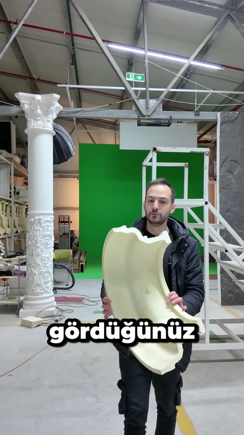 Un artigiano mostra verso la telecamera la superficie interna di un profilo curvo in poliuretano.