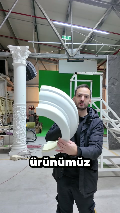 Un artigiano nell'officina presenta con entrambe le mani un profilo decorativo curvo e spesso.