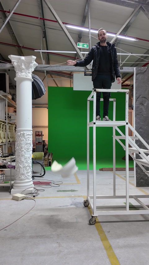 Decorative column capital drops from an elevated platform inside the workshop.