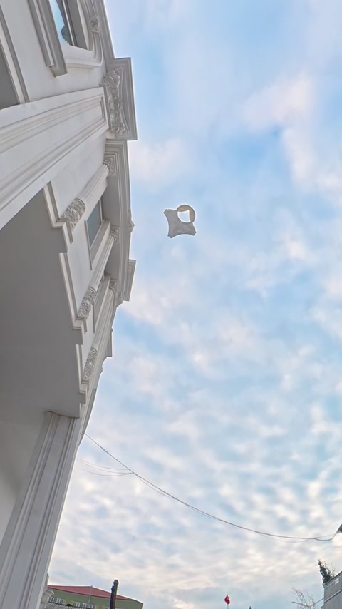 Decorative polyurethane piece appears airborne between buildings during drop testing.
